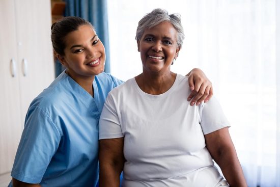 Adult daughter sitting next to her mom in an inpatient hospital.