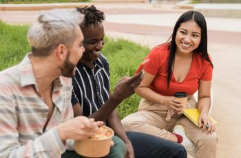 Happy friends having fun eating take away food outdoor in the city