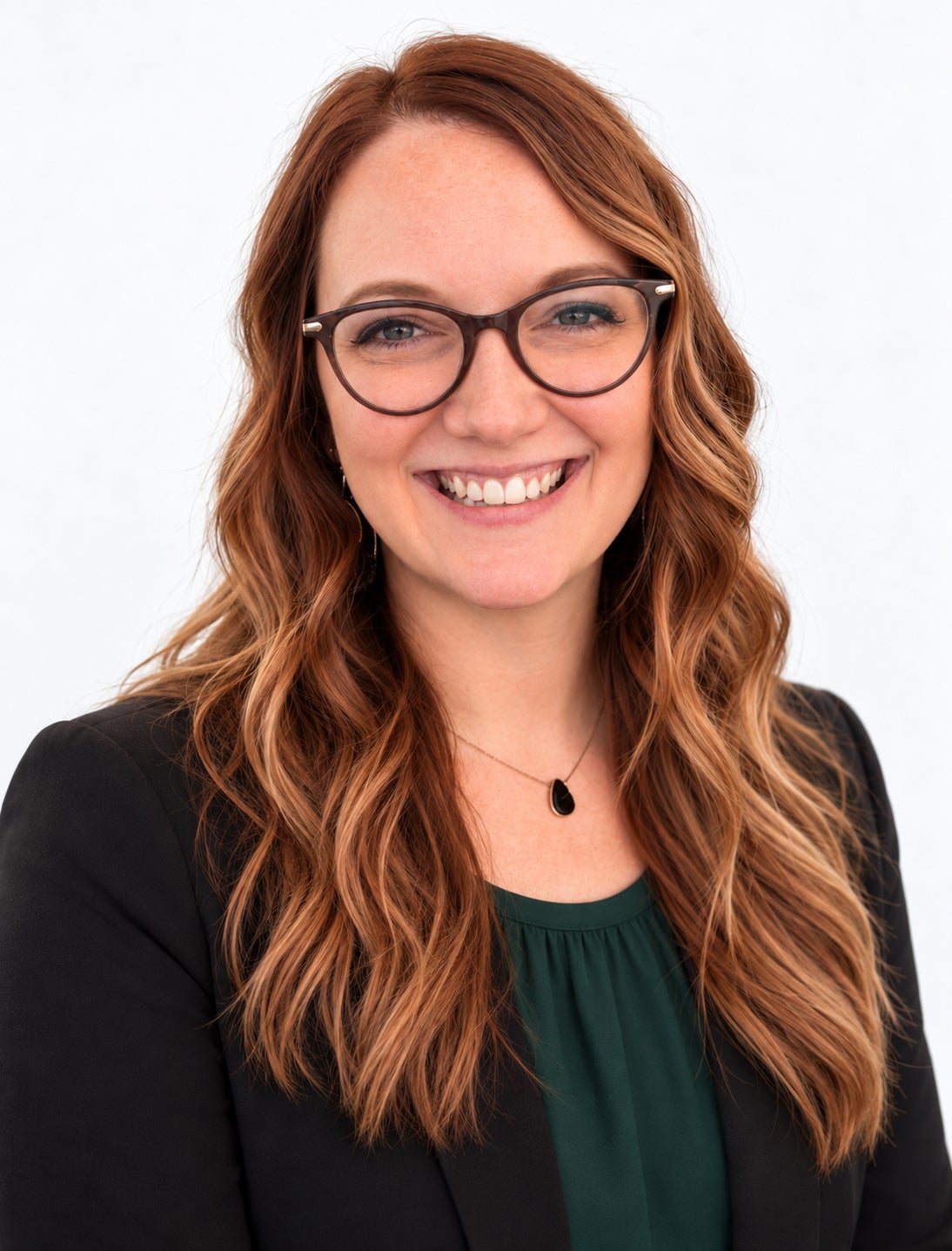 Alannah Rosenbalm wearing glasses, a black blazer, and a dark green top against a white background.