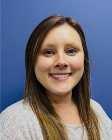 Amandabelle Dawdy smiling in a head-and-shoulders portrait against a blue background.
