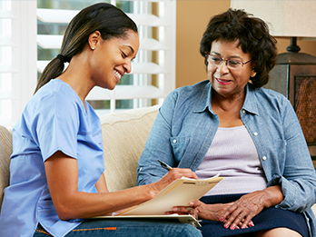 Health Home Care Coordinator completing paperwork with female patient at her home.