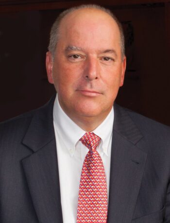 headshot of man wearing suit with redtie