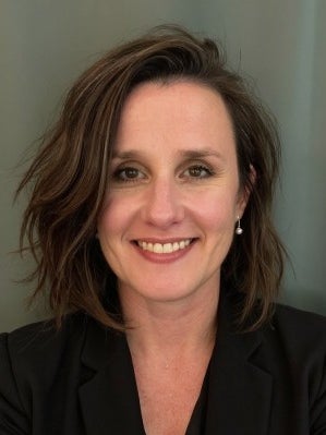Dr. Jessica Stembel smiling in a black blazer against a gray background.