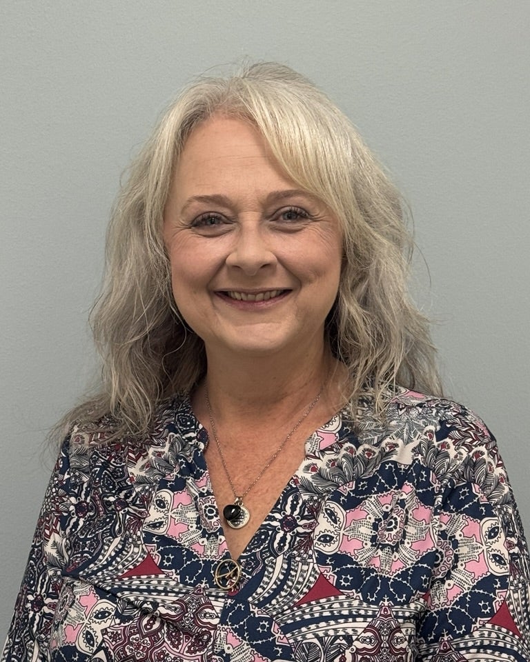 Portrait of Laurie Chesser smiling against a light gray background.