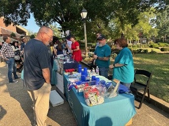 Centerstone staff at an outdoor event booth beneath a tent on a sunny day promoting 988 Crisis Services.