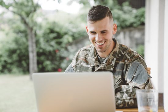 Smiling man in army uniform calling home from a mission