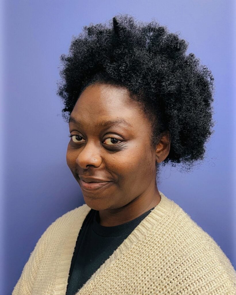 Tawanna Stevens wearing a cream knit cardigan against a blue background.