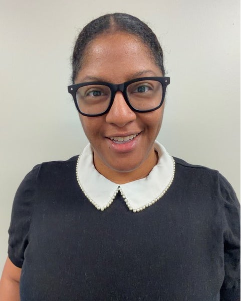Head-and-shoulders portrait of Taylor Holloway wearing black glasses and a dark top with a white collar.