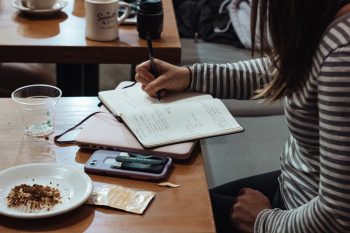 girl writing in journal in coffee shop