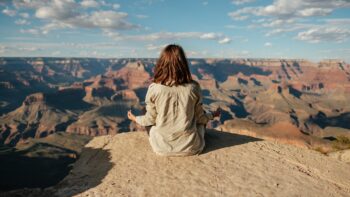 woman meditating on cliff with canyons in background