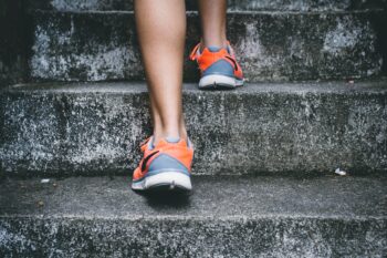 close up of orange and gray sneakers going up concrete steps