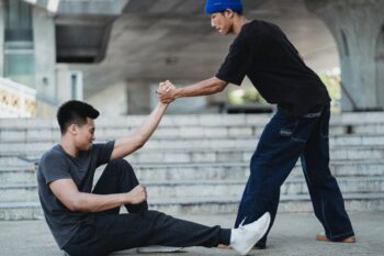 young man helping another young man get to his feet from the ground