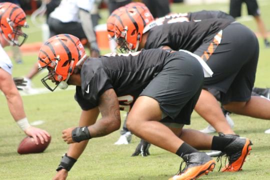 football player wearing orange helmet and black clothes in ready position