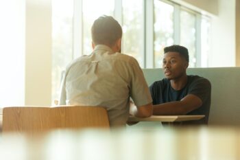 two young men sitting at table indoors