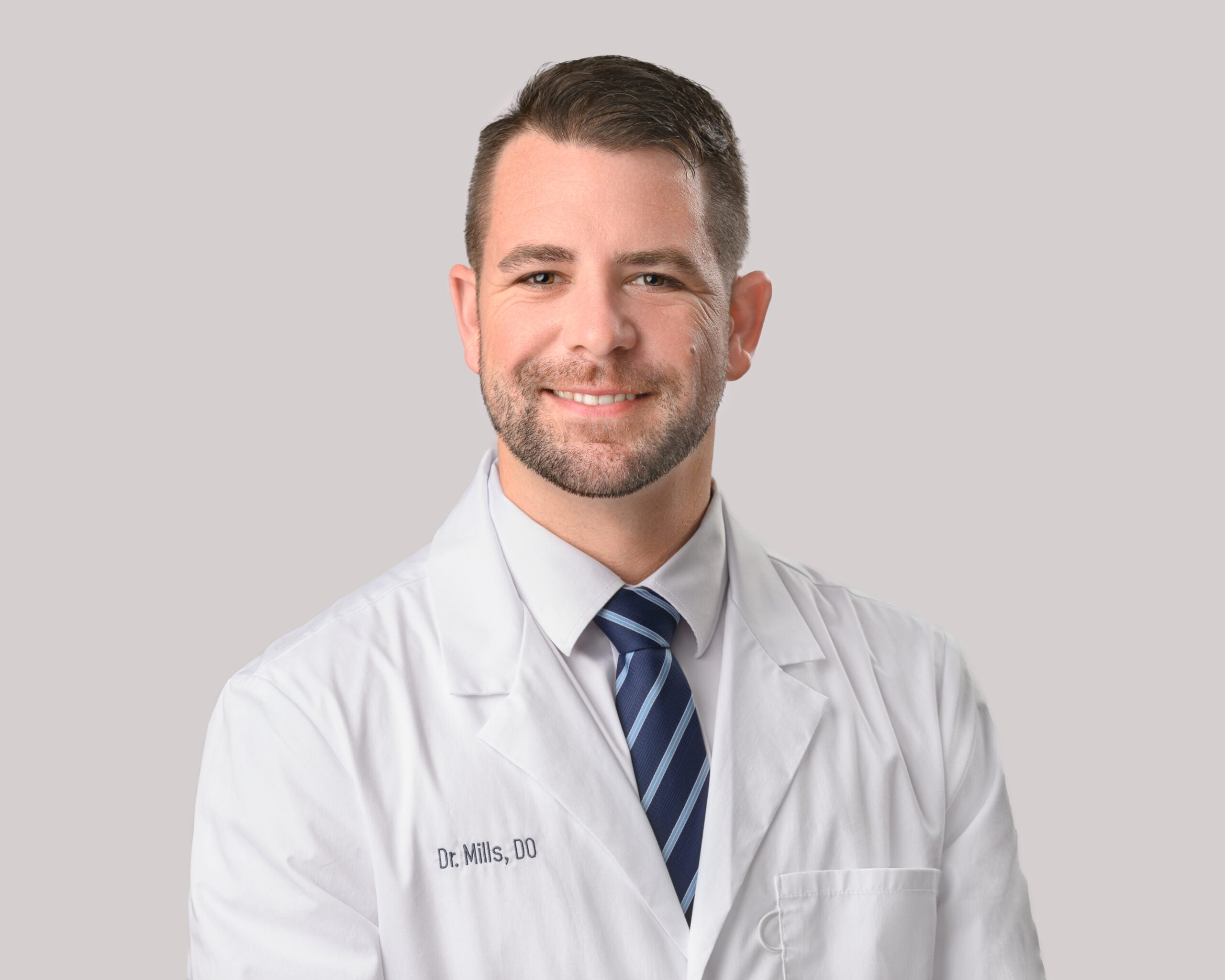 Portrait of Brian Mills, D.O. in a white lab coat