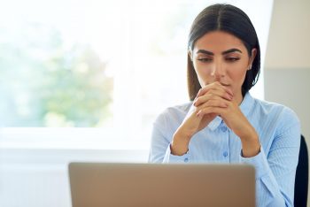A woman staring at a computer screen, doing research to help make a big decision