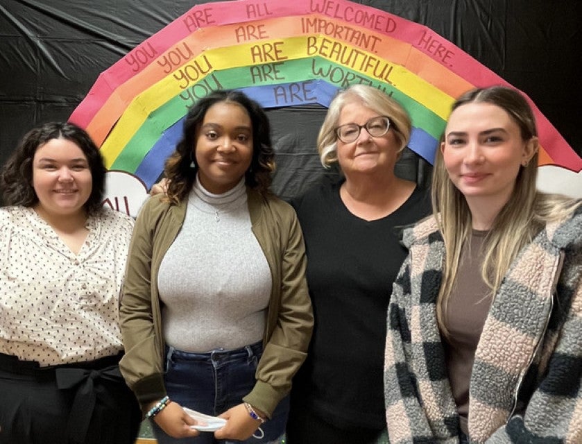 Tennessee Psychosocial A small group of Centerstone Psychosocial staff posing for a photo in front of a rainbow backdrop with inclusive messaging.