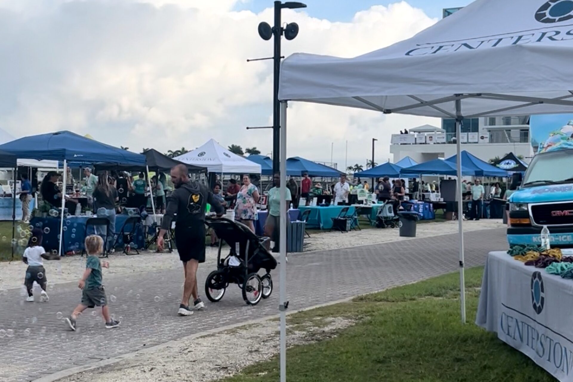 Several event tables and tents setup at an outdoor event on a sunny morning.