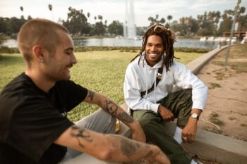 man in black t shirt sitting next to man in white long sleeve shirt