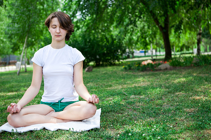 Woman meditating in a park to help control mood