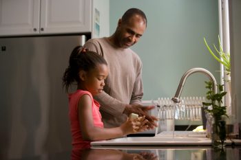 daughter washing hands with father guiding