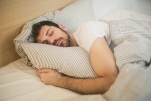 man holding pillow sleeping in bed