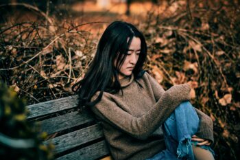 young woman sitting on bench in woods