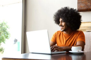 Happy student sitting at table with laptop Happy student sitting at table with laptop