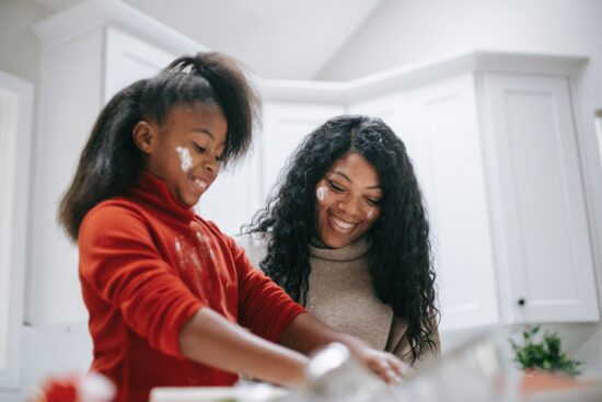 mother and daughter in kitchen with flour on faces