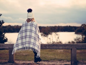 woman sitting on bench looking at pond